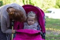 Woman looking at offended little girl sitting in stroller Royalty Free Stock Photo