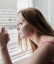 Woman looking out through venison blinds Royalty Free Stock Photo