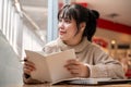 A woman is looking out the window and daydreaming while reading a book in a coffee shop Royalty Free Stock Photo