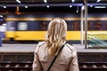 Woman looking at passing train at railroad station Royalty Free Stock Photo