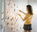 Woman looking at photos hanging with decoration lights on the white wall Royalty Free Stock Photo