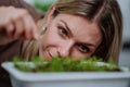 Woman looking at pot with cress growing from seed at home.