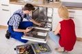 Woman Looking At Repairman Repairing Dishwasher Royalty Free Stock Photo