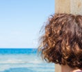 Woman looking at the sea horizon on a beautiful sunny summer day. Useful to indicate concepts of happiness, sadness, amazement,