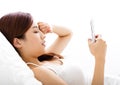 woman looking smart phone with tired eyes on the bed