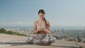 Woman looking at smartphone screen in city. Lady sitting in lotus pose on mat Royalty Free Stock Photo