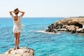 Woman looking on the stunning views from the famous Cape Greco viewpoint as she stands on the edge of a cliff