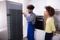 Technician Repairing Refrigerator In Kitchen Royalty Free Stock Photo