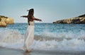 Woman looking thoughtful at sea water in summer holiday enjoying vacation relaxed wearing white beach dress