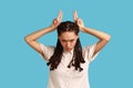 Woman looking threatening showing bull horn sign, holding fingers on her head, conflicting person. Royalty Free Stock Photo