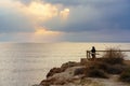 Woman looking to the horizon from a viewpoint at golden sunset over the sea. Royalty Free Stock Photo