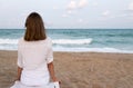 Woman looking to a tidal waves roll onto a sandy beach Royalty Free Stock Photo