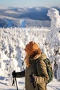 Woman looking to winter mountains from viewpoint during hiking in snowy forest Royalty Free Stock Photo