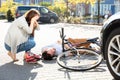 Woman looking at unconscious male cyclist lying on street Royalty Free Stock Photo