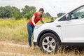 Woman looking under the hood of overheated car at meadow Royalty Free Stock Photo