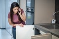 Woman looking under kitchen sink talking on smartphone