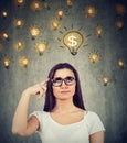 Woman looking up at dollar idea light bulbs above head deciding how to earn morney Royalty Free Stock Photo