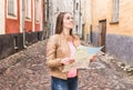 Woman looking up and holding map. Smiling traveler sightseeing.