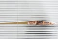 Woman Looking Through Venetian Blinds