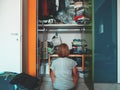 Woman looking at wardrobe, home interior, desperate housewife, cleaning home, rear view sitting, toned vintage style. Royalty Free Stock Photo