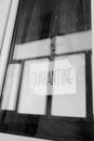 Woman looking through the window and holding a handwritten sign saying `Quarantine`.