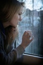 Woman looking through window with raindrops