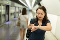 Woman looking at wristwatch at subway station