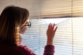 A woman looks through the blinds at the early morning sunlight. Royalty Free Stock Photo