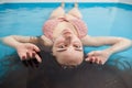 Woman looks at the camera lying in the water of a saltwater pool. Spa treatments.