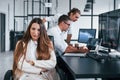 Woman looks into the camera. Team of stockbrokers works in modern office with many display screens Royalty Free Stock Photo