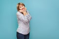 A woman in a blouse and jeans stands on a blue green background Royalty Free Stock Photo