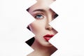 Woman looks into the hole of torn paper, bright beautiful makeup, big eyes and lips, bright lipstick, professional cosmetics and Royalty Free Stock Photo