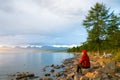 A woman looks at the lake Hovsgol in the sunset light. Peak Munku-Sardyk - near the center of the frame on the left. Mongolia.