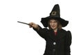 Woman looks like sorceress isolated on isolated white background. Woman wears black pointed hat, coat with magic wand