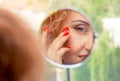 Woman looks in the mirror noticing the first wrinkles Royalty Free Stock Photo