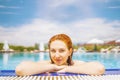 Woman looks out of the pool, hanging on railing. Royalty Free Stock Photo