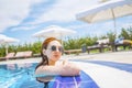 Woman looks out of the pool, hanging on the railing. Royalty Free Stock Photo