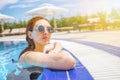 Woman looks out of the pool, hanging on railing. Royalty Free Stock Photo