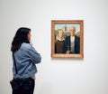 A woman looks at a painting in a Museum