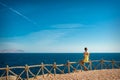 Woman looks at the sea and the island of Tiran