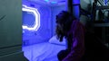 Woman looks with surprise at the Sleepbox with neon lights, the space capsule container for sleeping at the airport