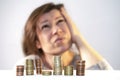 Woman looks up thoughtfully and tensely in front of stacks of coins. Search for a way out of poverty Royalty Free Stock Photo