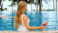 Woman lounging in infinity pool at luxurious hotel while drink tropical cold watermelon red cocktail Royalty Free Stock Photo