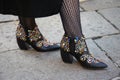 Woman with low leather boots decorated with colorful gems and studs before Bottega Veneta fashion show, Milan