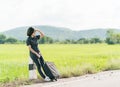 Woman with luggage hitchhiking along a road Royalty Free Stock Photo