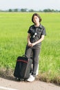 Woman with luggage hitchhiking along a road Royalty Free Stock Photo