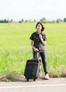 Woman with luggage hitchhiking along a road Royalty Free Stock Photo