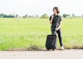 Woman with luggage hitchhiking along a road Royalty Free Stock Photo