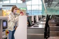 Woman with luggage over flight cancellation, stands at empty check-in counters at airport terminal due to coronavirus pandemic Royalty Free Stock Photo