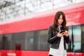 Woman with luggage at station traveling by train. Young tourist with cellphone and baggage on platform waiting for Royalty Free Stock Photo